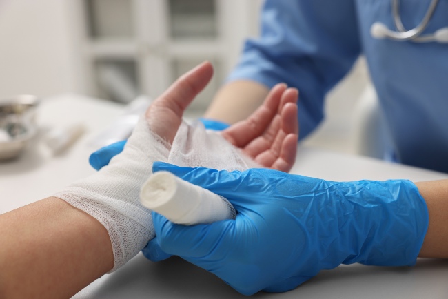 Doctor bandaging a patient’s hand after wound care treatment in Dallas, TX