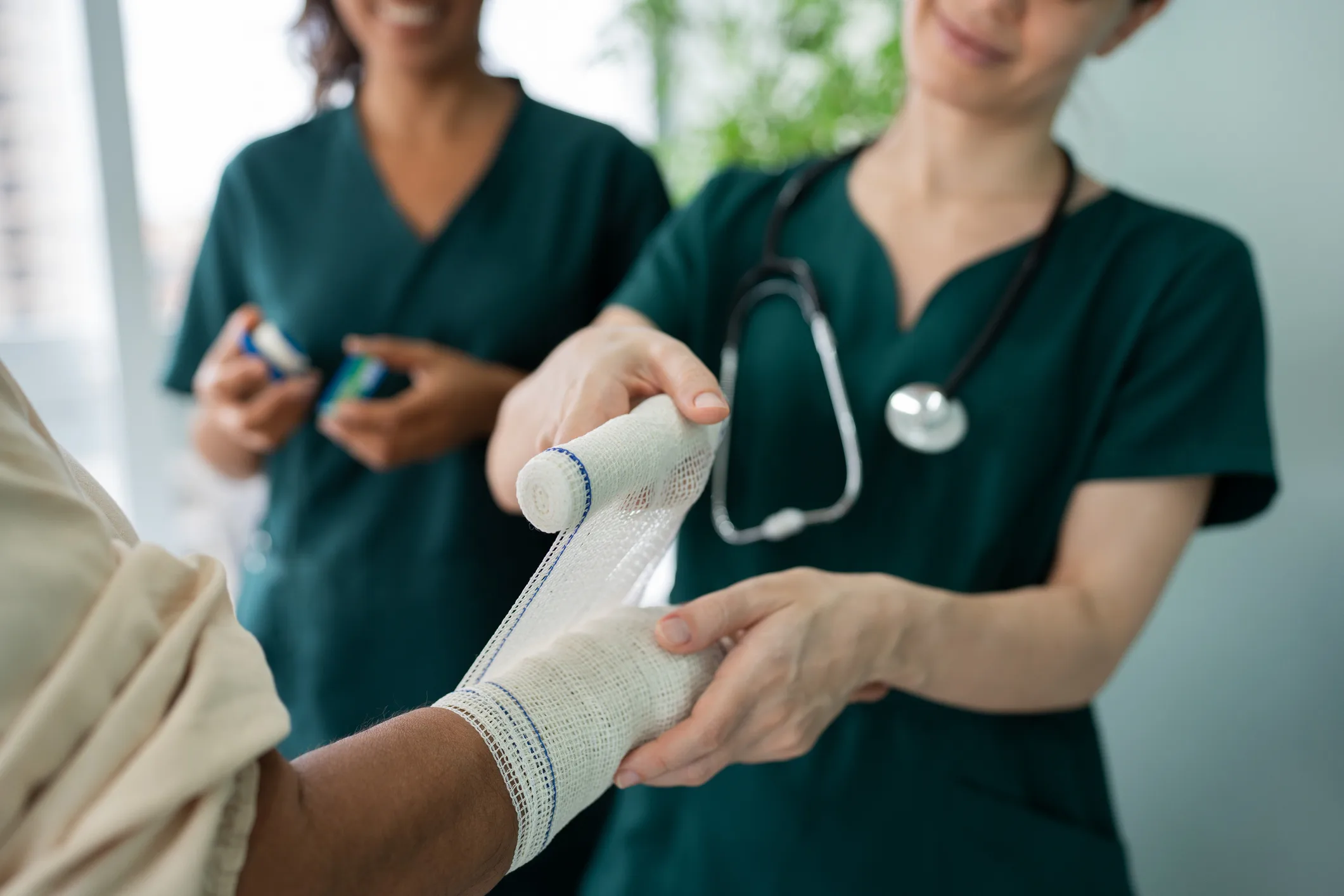Healthcare professionals wrapping a bandage around a patient's arm during wound care in Dallas, TX